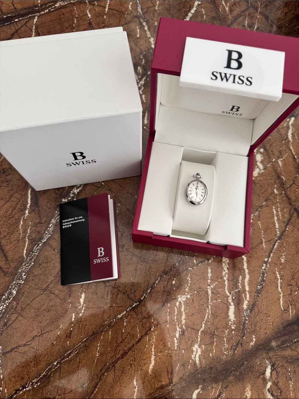 B Swiss Women's Silver Oval Bracelet Watch with White Display.